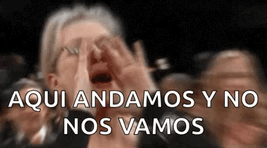A Woman Is Screaming In A Crowd Of People While Covering Her Face . GIF