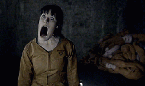 A Woman Is Screaming In A Dark Room With A Triangle Logo On Her Jacket GIF
