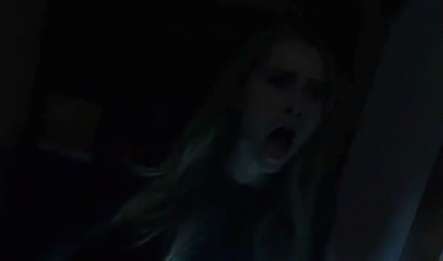 a woman is screaming in a dark room with her mouth wide open .