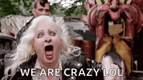 A Woman Is Screaming In Front Of A Carnival Ride While A Man Is Standing Behind Her . GIF