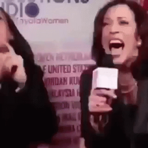 A Woman Is Screaming Into A Microphone In Front Of A Sign That Says United States . GIF
