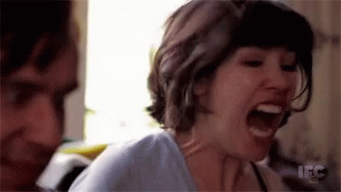 A Woman Is Screaming With Her Mouth Open And A Man Is Standing Behind Her . GIF
