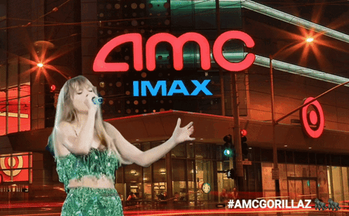 A Woman Is Singing In Front Of An Amc Imax Sign GIF