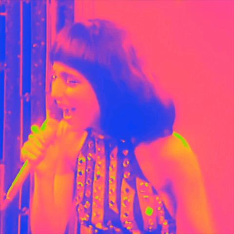 A Woman Is Singing Into A Microphone In A Colorful Image GIF