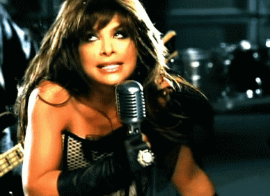 A Woman Is Singing Into A Microphone In A Dark Room GIF