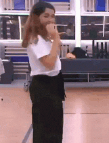 A Woman Is Singing Into A Microphone In A Room . GIF