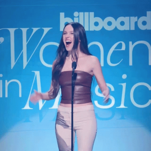 Woman Singing Into Microphone In Front Of Billboard GIF