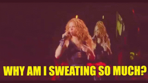 a woman is singing into a microphone on a stage and the words `` why am i sweating so much '' are above her .