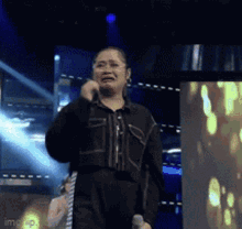 A Woman Is Singing Into A Microphone On A Stage While Crying . GIF