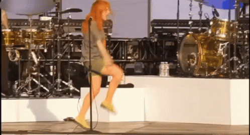 A Woman Is Singing Into A Microphone On Stage GIF