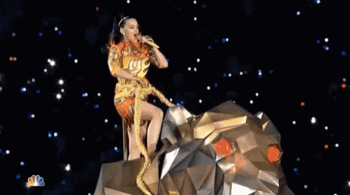 A Woman Is Singing Into A Microphone While Sitting On Top Of A Statue Of A Lion . GIF