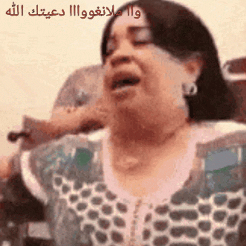 A Woman Is Singing Into A Microphone With Arabic Writing On The Bottom GIF