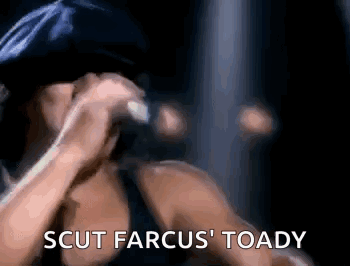 A Woman Is Singing Into A Microphone With The Words `` Scut Farcus ' Toady '' Written Below Her . GIF
