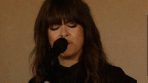 A Woman Is Singing Into A Microphone With The Words Sie7evec Written In The Background GIF