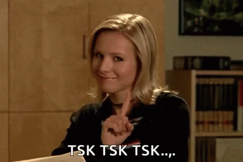 A Woman Is Sitting At A Desk And Pointing At Something . GIF
