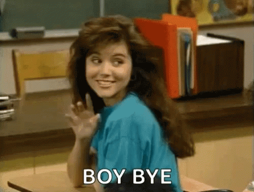 A Woman Is Sitting At A Desk In A Classroom Waving And The Words Boy Bye Are Visible . GIF