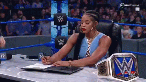 A Woman Is Sitting At A Desk In A Wrestling Ring Signing A Contract . GIF