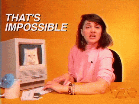 A Woman Is Sitting At A Desk In Front Of A Computer With A Cat On The Screen . GIF