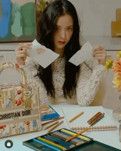 A Woman Is Sitting At A Desk With A Christian Dior Bag GIF