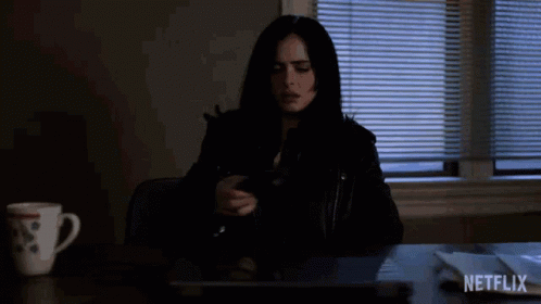 A Woman Is Sitting At A Desk With A Laptop And A Cup Of Coffee And A Netflix Logo In The Corner . GIF