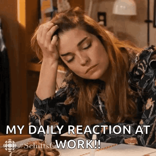 A Woman Is Sitting At A Desk With Her Head In Her Hand And The Words " My Daily Reaction At Work " Below Her GIF