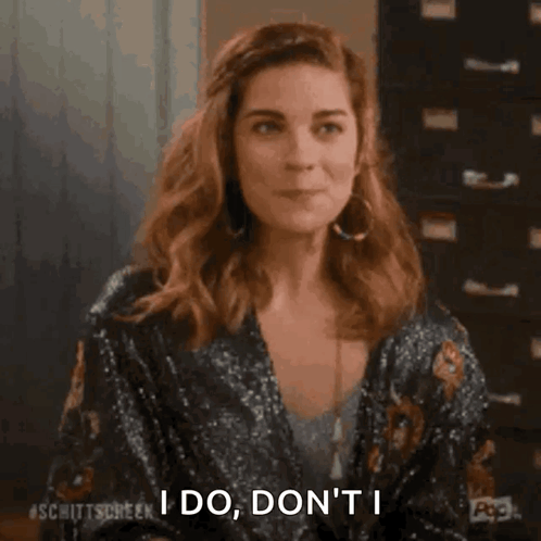 A Woman Is Sitting At A Table And Smiling While Holding Her Hair . GIF