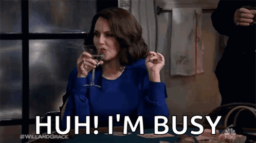 A Woman Is Sitting At A Table Drinking A Glass Of Wine And Saying I 'M Busy . GIF