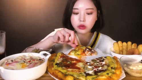 A Woman Is Sitting At A Table Eating A Pizza . GIF