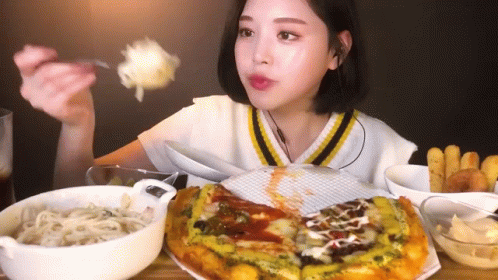A Woman Is Sitting At A Table Eating A Pizza With A Fork And Spoon . GIF