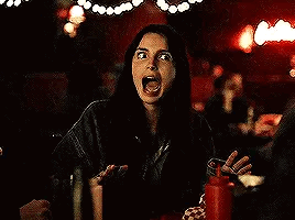 A Woman Is Sitting At A Table In A Dark Room With A Ketchup Bottle . GIF