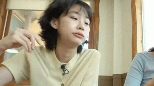 A Woman Is Sitting At A Table In A Restaurant With A Microphone In Her Hair . GIF