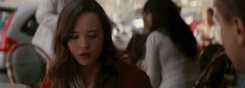 A Woman Is Sitting At A Table In A Restaurant With Her Eyes Closed And A Man Is Standing Behind Her . GIF