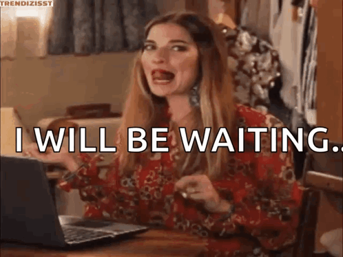 A Woman Is Sitting At A Table In Front Of A Laptop Computer And Saying `` I Will Be Waiting '' . GIF