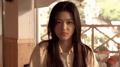 A Woman Is Sitting At A Table In Front Of A Window In A Restaurant . GIF