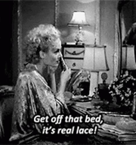 A Woman Is Sitting At A Table Talking On A Cell Phone In A Bedroom . GIF