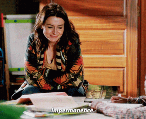 A Woman Is Sitting At A Table With A Book And Says Impermanence GIF