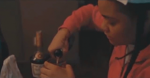 A Woman Is Sitting At A Table With A Bottle Of Wine In Her Hands . GIF