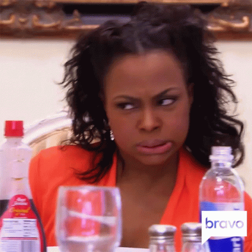 A Woman Is Sitting At A Table With A Bravo Logo On The Bottom GIF