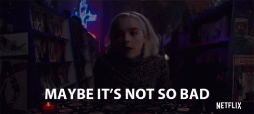 A Woman Is Sitting At A Table With A Candle In Front Of A Bookshelf In A Bookstore . GIF