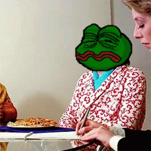 A Woman Is Sitting At A Table With A Frog On Her Head GIF
