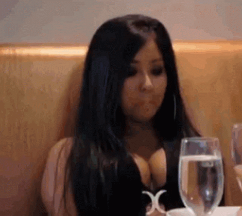 A Woman Is Sitting At A Table With A Glass Of Water And A Glass Of Wine . GIF