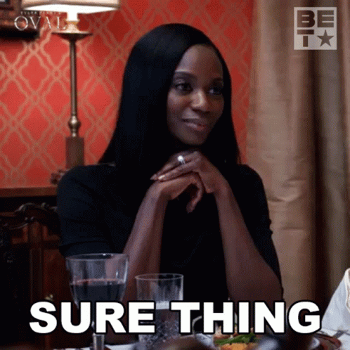 A Woman Is Sitting At A Table With A Glass Of Wine And Says Sure Thing GIF