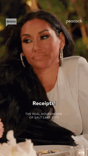 A Woman Is Sitting At A Table With A Plate Of Food And A Peacock Logo Behind Her GIF
