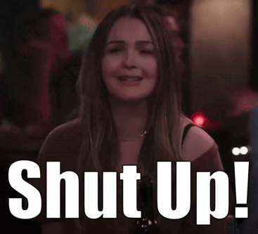 A Woman Is Sitting At A Table With A Sign That Says Shut Up ! GIF