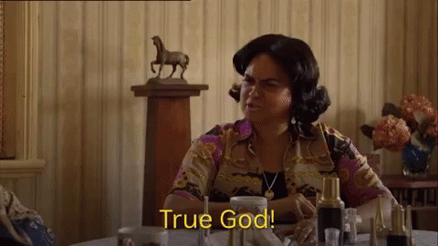 A Woman Is Sitting At A Table With A Statue Of A Horse In The Background . GIF