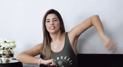 A Woman Is Sitting At A Table With Her Arms Outstretched . GIF