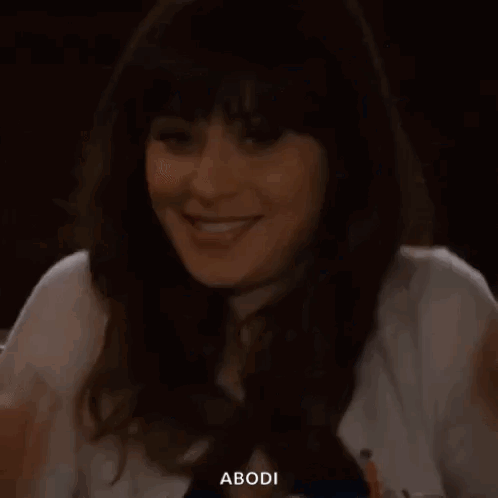 A Woman Is Sitting At A Table With Her Hand On Her Face And Smiling . GIF