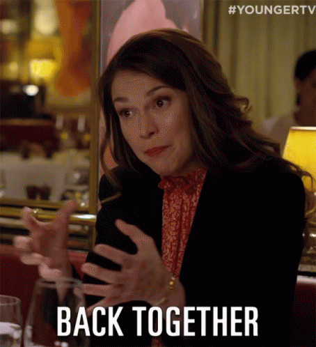 A Woman Is Sitting At A Table With Her Hands Out And The Words Back Together Written Below Her GIF