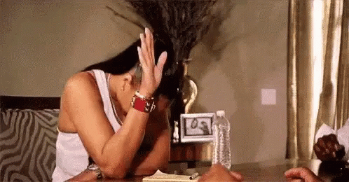 A Woman Is Sitting At A Table With Her Head In Her Hands . GIF