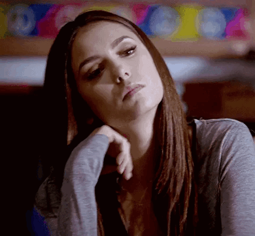 A Woman Is Sitting At A Table With Her Head Resting On Her Hand . GIF